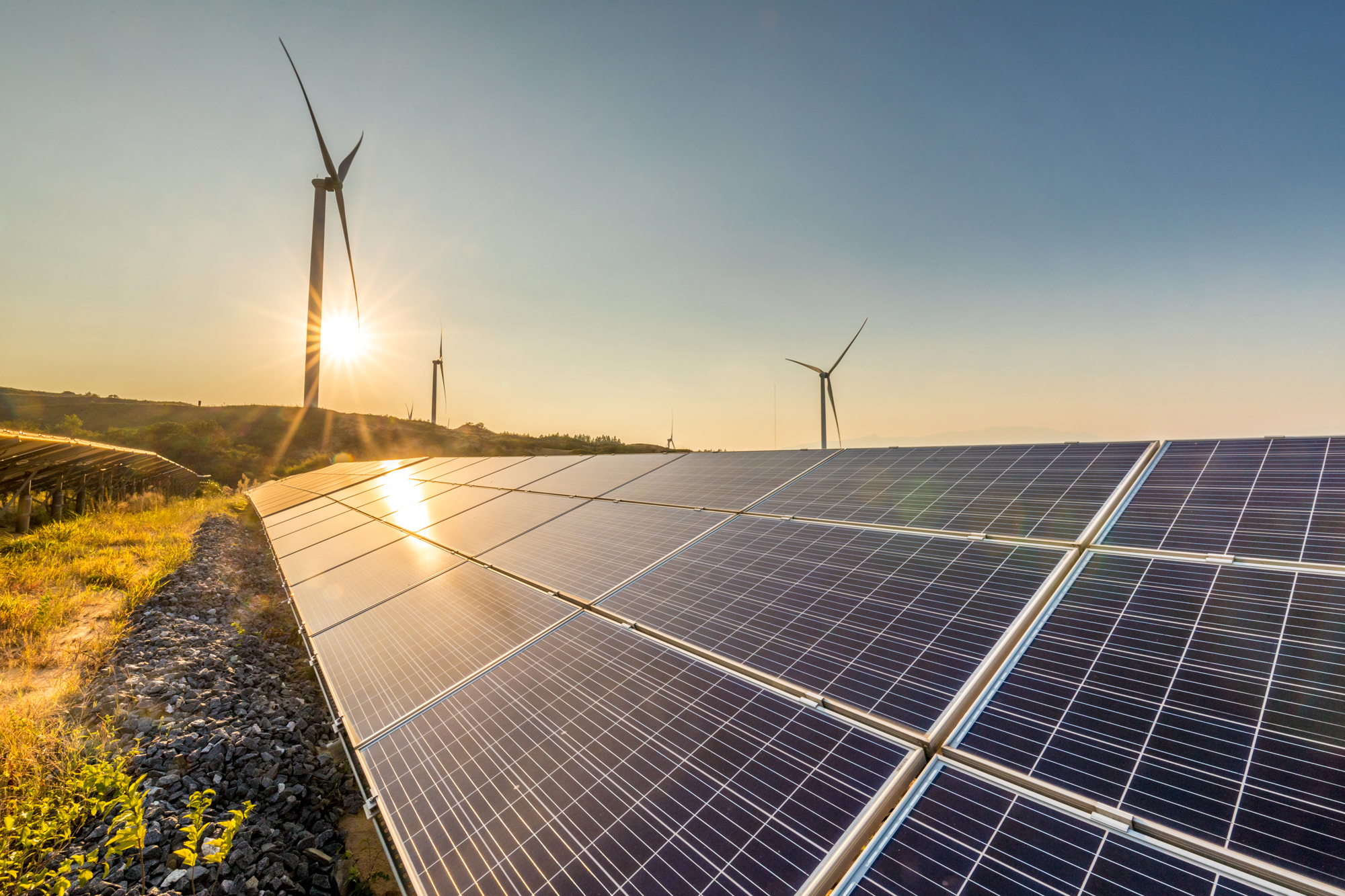 Solceller med vindkraft i bakgrunden